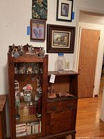 Overall view of oak display cabinet with glass door, side storage, drawer and wall art above