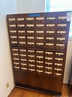 Front view of wooden cabinet with 60 closed drawers and label holders
