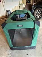 Front view of green canvas portable foldable dog crate showing mesh window and EliteField brand label.