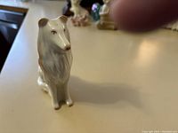 Front angle close-up of the white porcelain Collie figurine with painted brown accent details, sitting posture.