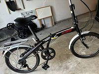 Side view of black X-Spec folding bike showing gear drivetrain, seat, and frame branding.