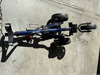 Top-down view of folded blue golf pull cart with three wheels and handle.