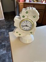 White porcelain clock shaped like Ireland with shamrocks, standing on a pedestal base.