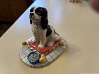 Side view of Royal Doulton King Charles Spaniel figurine showing detailed texture and color of dog, cushion, and food bowl.