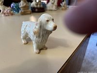 Side angle view of the Belleek Spaniel porcelain figurine showing detailed fur texture and brown accents on ears and nose.