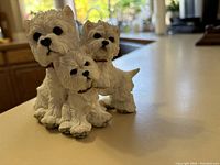 Front angle of the three Westie dog figurines on a light surface showing detailed facial features and collars.
