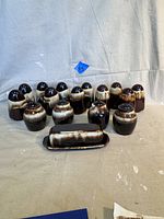 15 vintage Pfaltzgraff salt and pepper shakers arranged with brown and cream drip glaze and accompanying butter dish.