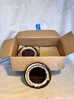 Opened cardboard box showing stacked vintage brown drip Pfaltzgraff salad plates with one plate in front for clear view.