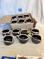 19 ceramic sugar and creamer containers, mostly inside a worn cardboard box, all brown drip glaze and white porcelain edges