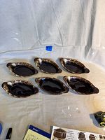 All six brown drip oval casserole dishes laid out on a beige cloth.