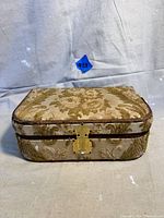 Antique fabric-covered jewelry box with floral pattern and brass lock, shown closed from front view.