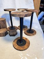Wooden circular bases mounted on black metal stands showing height and finish
