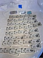 Photo showing a large spread of multiple fifty-centavos Philippine banknotes arranged in rows on a light fabric background.