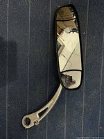 Mirror with reflective surface clearly showing the environment and clamp arm in detail.