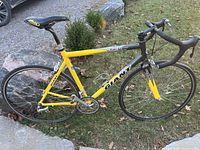 Left side view of the entire bike showing yellow and black frame, wheels, saddle and pedals