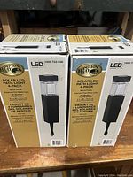 Two unopened boxes of Hampton Bay Solar LED Path Light 4-Packs showing front and side views.