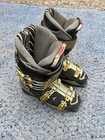 Pair of Head men’s downhill ski boots showing the outer side and front buckles on a blue blanket.