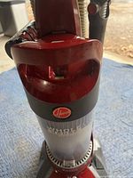 Close-up photo of the Hoover logo and handle on the vacuum cleaner with red casing and transparent dustbin below.