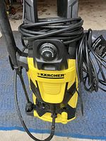 Front view of Karcher pressure washer showing pressure control knob and coiled hose.