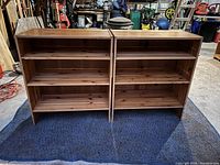 Front view of two knotty pine bookcases side by side, showing shelves and wood grain