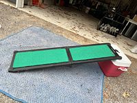 Side view of the Pet Gear dog ramp unfolded and resting on a blue textured mat outdoors.