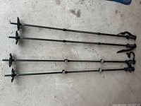 Four Snow Mountain walking/hiking poles laid side by side on concrete floor, showing full length, locking clasps, and basket near metal tips