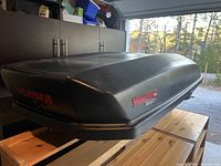 Side view of black Yakima Skybox cargo box showing Yakima branding and general shape.