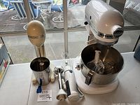 Photo of all three mixers together on table by window. From left to right: Hamilton Beach drink mixer with cup, Braun immersion mixer, KitchenAid stand mixer with bowl and attachments.