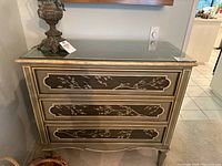 Full view of the dresser showing three drawers with painted cherry blossom design and glass top.