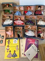 Overview of 12 boxed dolls and 3 books laid out on floor