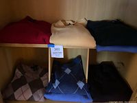 View of 6 folded cashmere sweaters showing variety of colors and patterns including solids and argyle