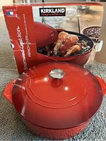 Red Kirkland Signature enameled cast iron French oven with its box showing the product image and branding. Made in France label visible.