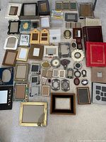 Full view of assorted picture frames and vintage photo albums arranged on carpeted floor.