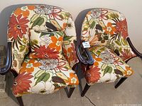 Pair of MCM chairs with large floral upholstery showing front view and included throw pillows
