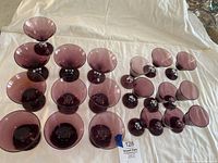 Top view showing 19 pieces of amethyst purple glass stemware arranged in groups by size and type, including champagne/dessert, smaller dessert, and aperitif glasses.