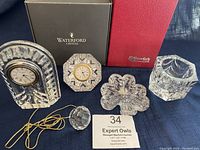 Group photo showing all five Waterford crystal items including desk clocks, shamrock decoration, votive holder, and hanging ball with original branded boxes.