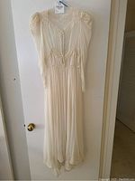 Front full view of vintage wedding dress hanging on door