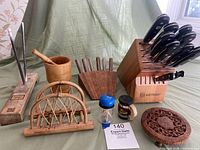 Full lot displayed showing wooden Wusthof knife block with knives, steak cutlery holder with knives, wooden mortar and pestle, sharpener with rods on wood base, napkin holder, decorative wooden trivet, and small containers.
