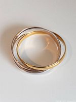 Three interlocked bangles showing yellow, rose and white gold tones