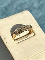 Close-up top view of ring on white stand showing diamond cluster detail