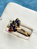 Front view of ring on white display showing sapphire and ruby cluster arrangement