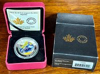 Coin in protective capsule inside red display case alongside black outer box