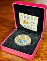 Red velvet display case holding the coin in a clear capsule with certificate card behind