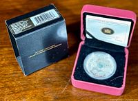 Coin and original packaging: red presentation box with foam insert and outer black cardboard box.