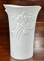 Front side showing curved embossed flower and wave patterns on matte white bisque porcelain surface.