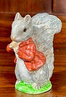 Front view showing detailed squirrel face, red jacket and green grass base