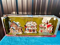 Set of three Holiday Time Vintage Collectibles porcelain Christmas village houses in original box showing all three houses together.