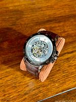 Front view of watch on stand showing skeleton dial and bezel