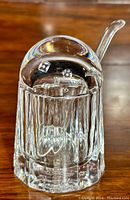 Front and side view of the clear crystal sugar bowl with dome lid and lucite spoon placed inside.