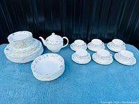 Full view of dinnerware set including stacked plates, cups with saucers, teapot, and sugar bowl showing floral pattern and condition.